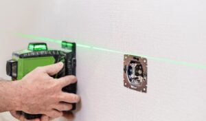 Specjalista wykonujący pomiar wilgotności ściany za pomocą profesjonalnego wilgotnościomierza.